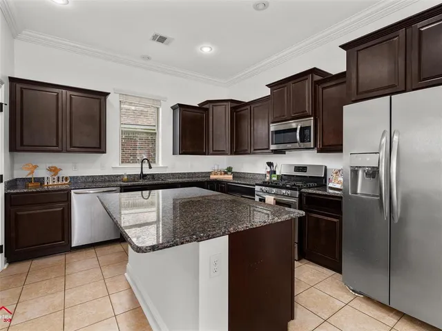 a kitchen with kitchen island granite countertop a refrigerator stove and microwave