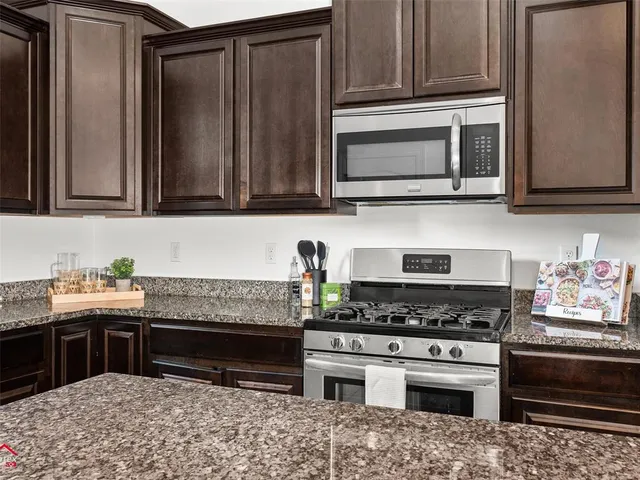 a kitchen with granite countertop a stove and a microwave