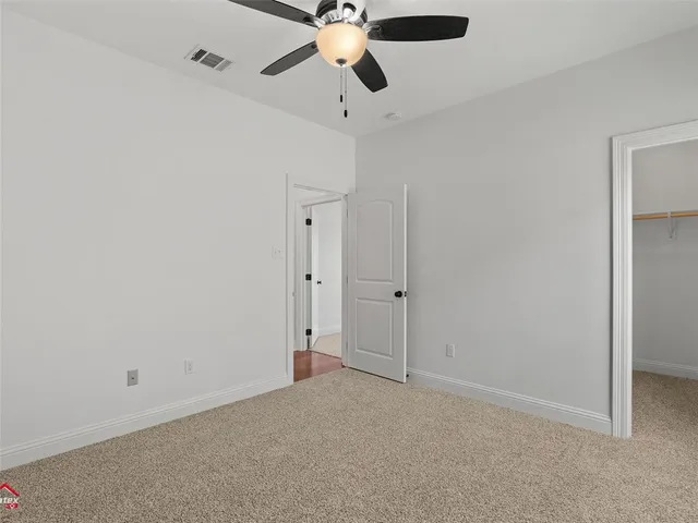 a view of an empty room and chandelier fan