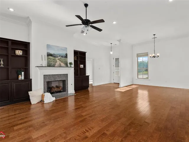 a view of empty room with wooden floor fireplace and window