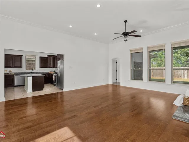 a view of a livingroom with a flat screen tv wooden floor and a ceiling fan