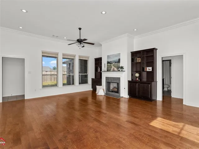 a view of an empty room with window and wooden floor