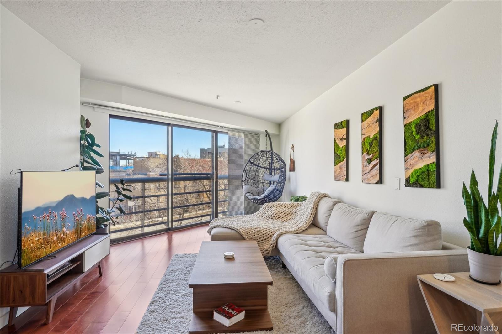 a living room with furniture large window and wooden floor