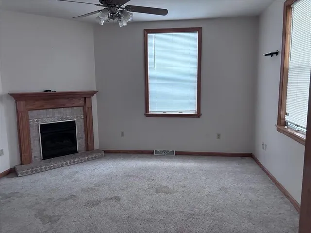 an empty room with a fireplace and windows