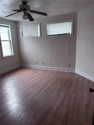 an empty room with wooden floor cabinet and windows