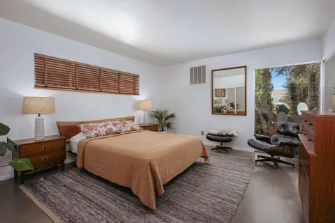 a bedroom with a bed and large windows