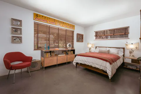 a bedroom with a bed and potted lamp