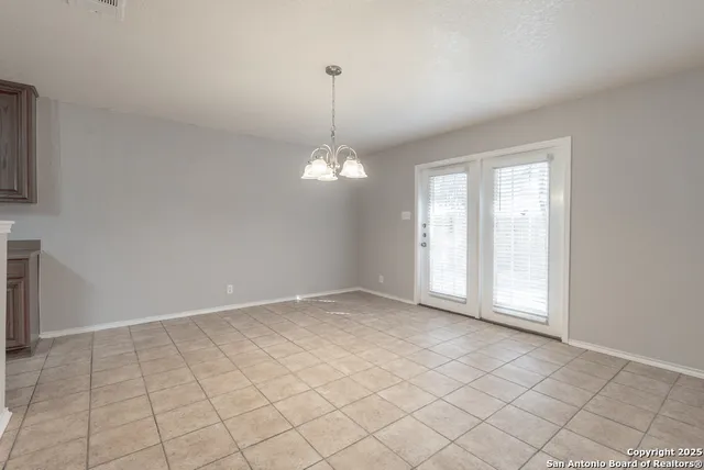 an empty room with chandelier fan and windows