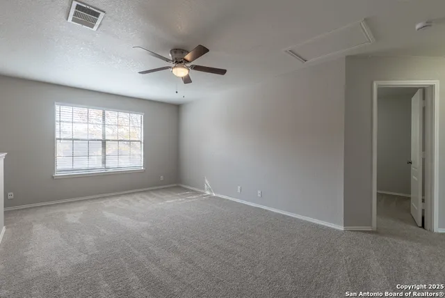 an empty room with windows and fan