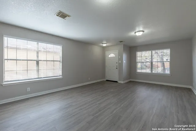 an empty room with wooden floor and windows
