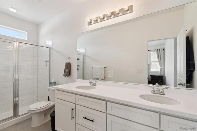 a bathroom with a double vanity sink toilet and shower