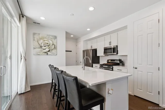 a kitchen with stainless steel appliances a microwave a stove a refrigerator a table and chairs