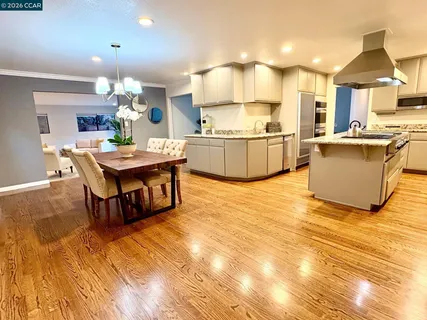 a kitchen with granite countertop a table chairs a sink dishwasher stove and cabinets with wooden floor