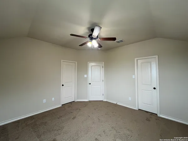 an empty room with closet and a ceiling fan