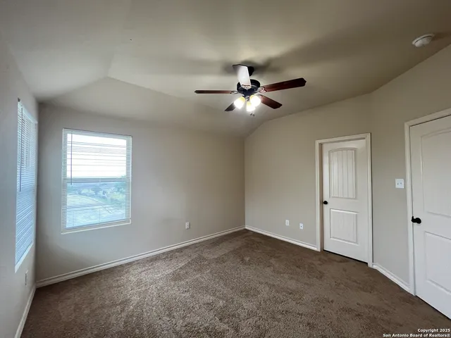 an empty room with chandelier fan and windows