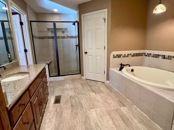 a bathroom with a granite countertop sink a mirror and shower