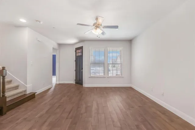 an empty room with wooden floor fan and windows