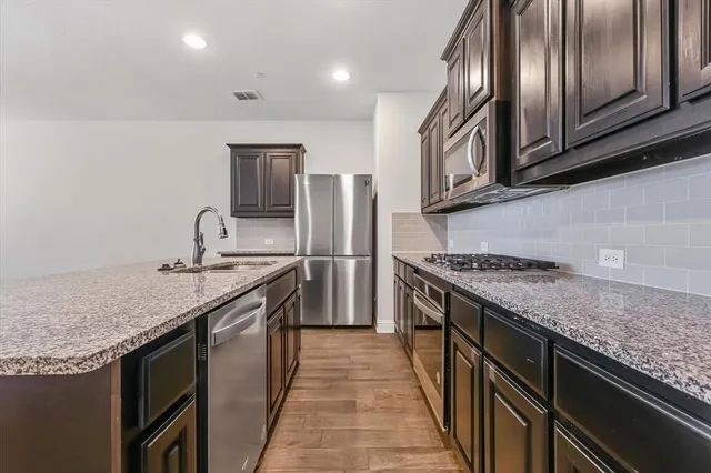 a kitchen with stainless steel appliances granite countertop a stove a sink dishwasher and refrigerator