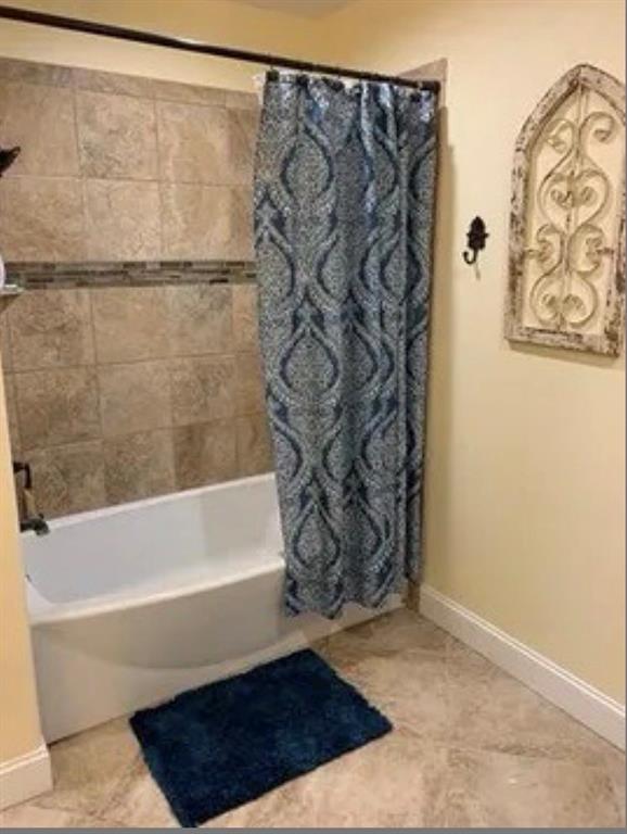 1794 Cr 527 Road Baird, TX 79504 - Photo 35 of 38 Bathtub with tiled surround, mosaic accent band, and a shower fixture