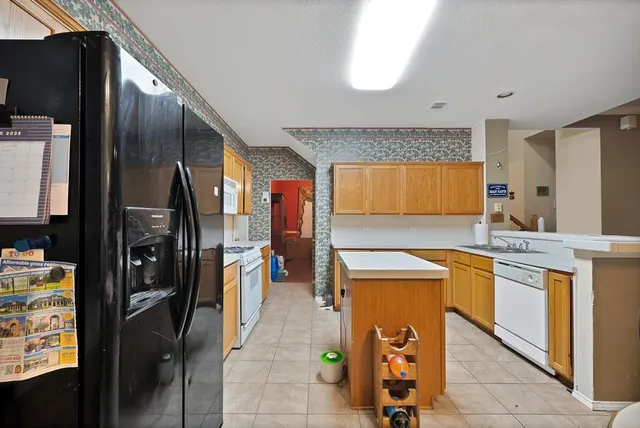 a kitchen with stainless steel appliances granite countertop a refrigerator a stove and a sink