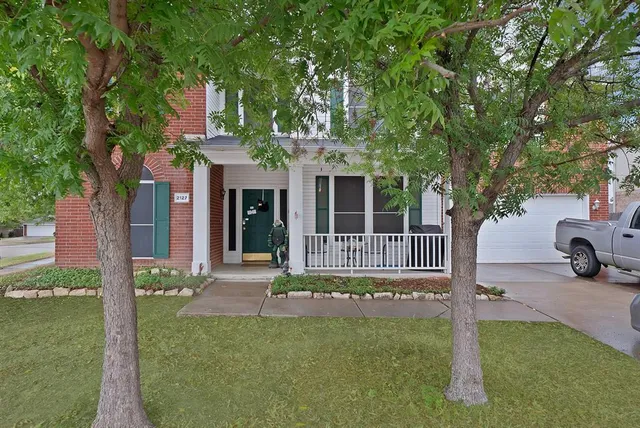 a view of a house with a small yard plants and large tree