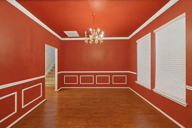 a view of an empty room with chandelier fan and wooden floor