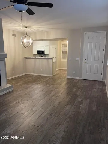 a view of an empty room with wooden floor and a fireplace