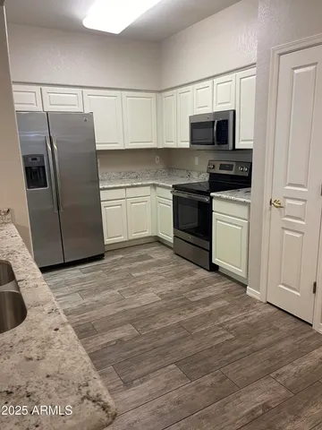 a kitchen with granite countertop a refrigerator and a sink