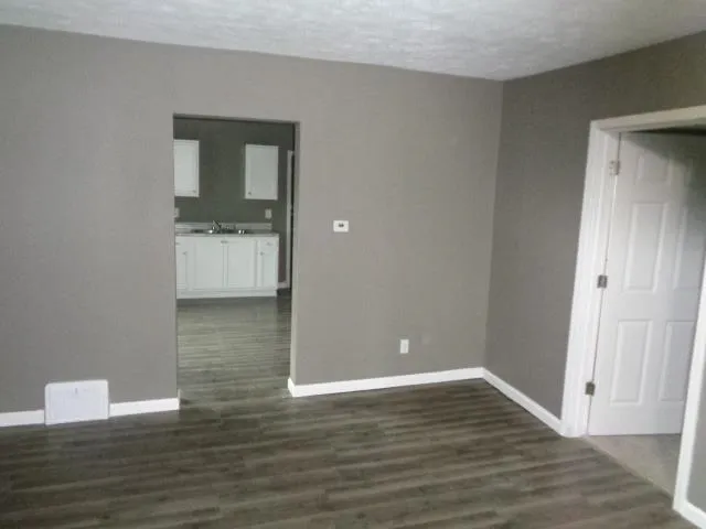 a view of kitchen with granite countertop white cabinets and sink
