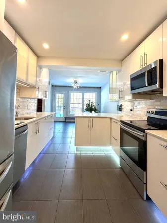 a large kitchen with a large counter top stainless steel appliances and cabinets