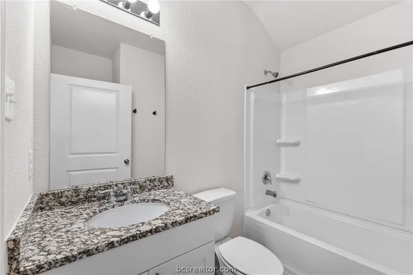 a bathroom with a granite countertop sink toilet and shower