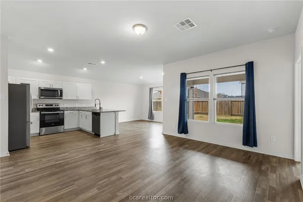 a view of kitchen with kitchen island wooden floor and stainless steel appliances