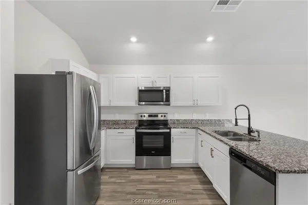 a kitchen with stainless steel appliances granite countertop a refrigerator stove and sink