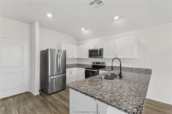 a kitchen with stainless steel appliances granite countertop a refrigerator and a sink