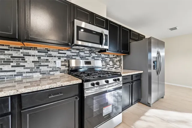 a kitchen with granite countertop a stove sink and cabinets