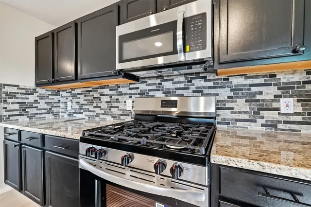 a kitchen with stainless steel appliances granite countertop a refrigerator a stove a sink and a microwave