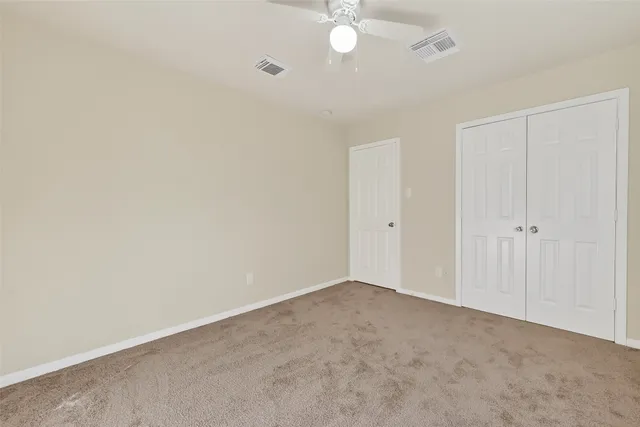 a view of an empty room with chandelier fan