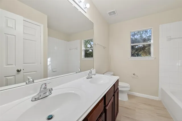 an empty room with windows and chandelier fan
