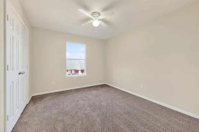 an empty room with a window and a ceiling fan