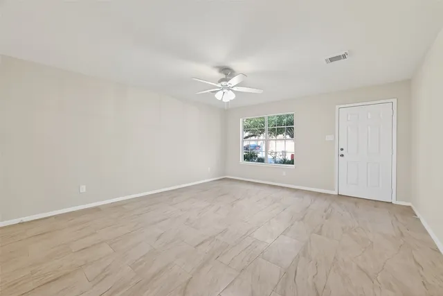 an empty room with wooden floor and ceiling fan