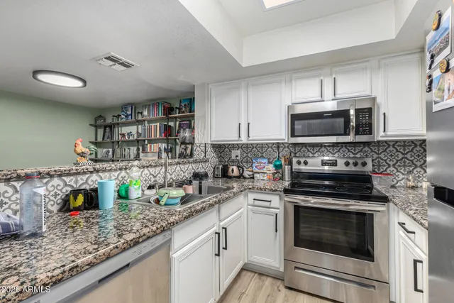 a kitchen with stainless steel appliances granite countertop a stove microwave and sink