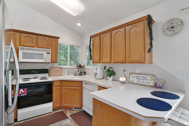 464 West Saddle Back Drive Springville, UT 84663 - Photo 7 of 15 Kitchen featuring wood-finish cabinetry, white countertops, built-in microwave, stainless steel refrigerator, and a corner sink with a window