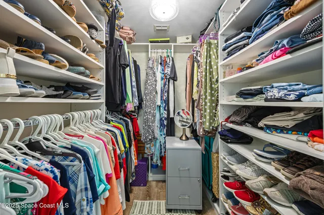 a view of walk in closet with clothes and shoes