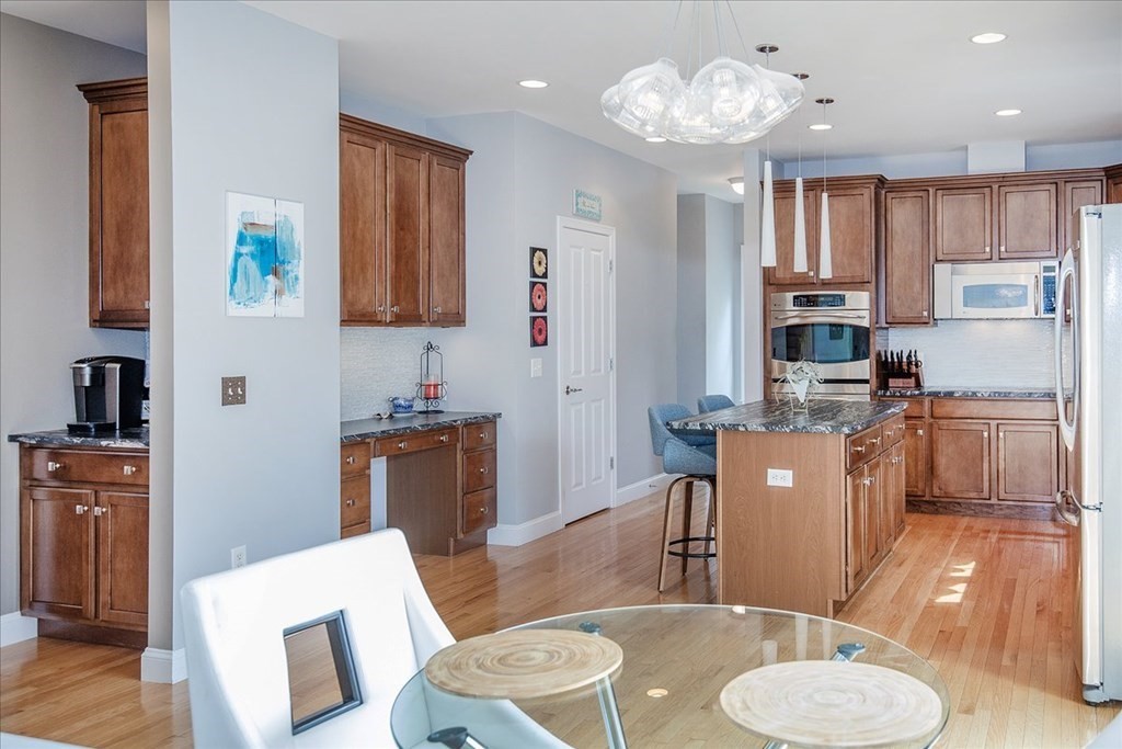 11 Sparrow Lane Danvers, MA 01923 - Photo 14 of 41 a kitchen with stainless steel appliances granite countertop a stove top oven a sink a dining table and chairs with wooden floor