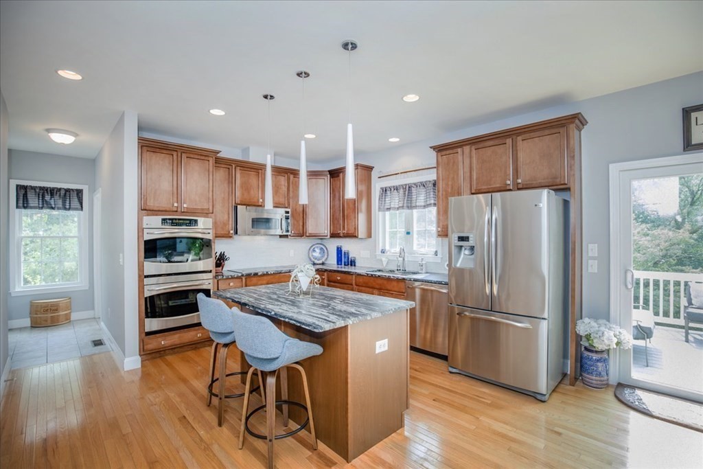 11 Sparrow Lane Danvers, MA 01923 - Photo 4 of 41 a kitchen with stainless steel appliances granite countertop a refrigerator a stove a sink a dining table and chairs with wooden floor
