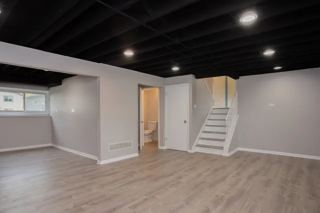 a view of an empty room with wooden floor and stairs