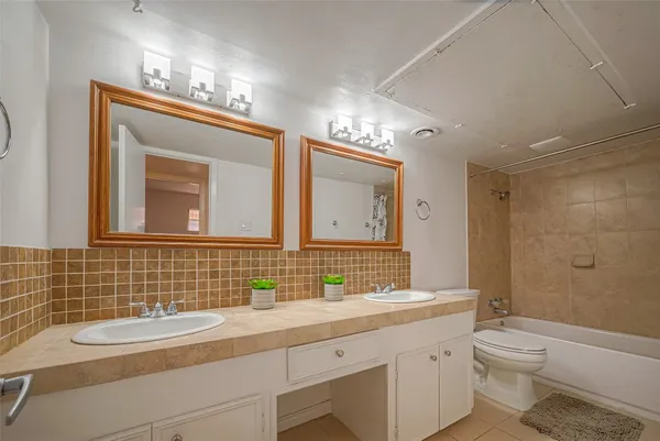 a bathroom with a double vanity sink toilet mirror and shower