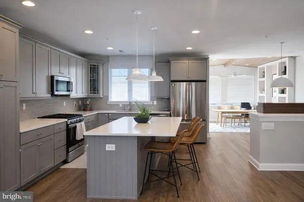 a kitchen with stainless steel appliances granite countertop a refrigerator a stove top oven a sink dishwasher and white cabinets with wooden floor