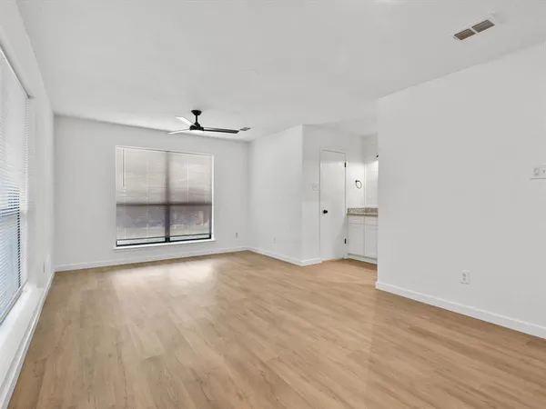 an empty room with wooden floor cabinet and windows