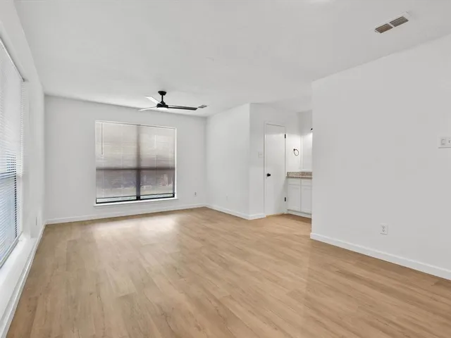 an empty room with wooden floor cabinet and windows